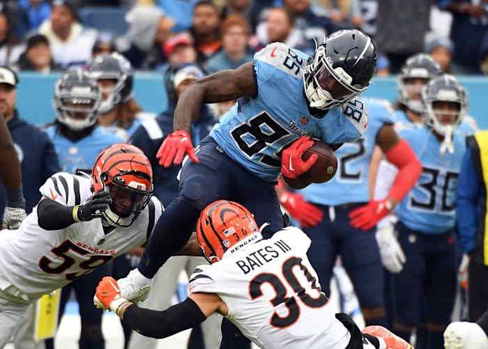 Tennessee Titans tight end Chigoziem Okonkwo (85) is stopped by Cincinnati Bengals linebacker Akeem Davis-Gaither (59) and safety Jessie Bates III (30) after a catch during the second half at Nissan Stadium.